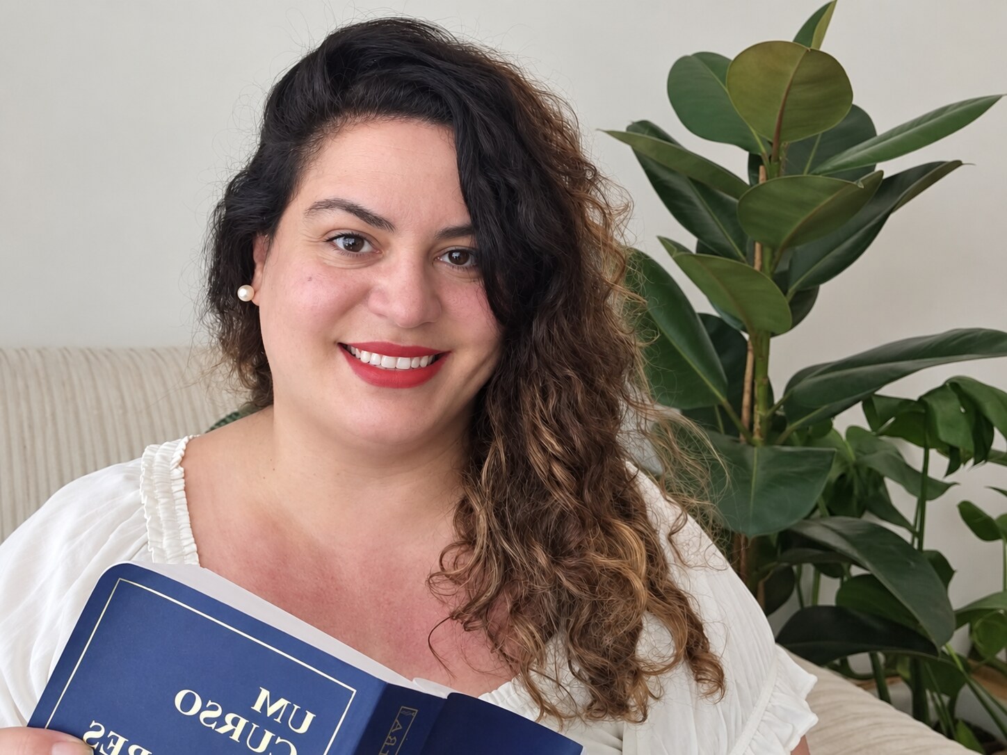 Bruna Andretto sorrindo e segurando um livro de Um Curso em Milagres